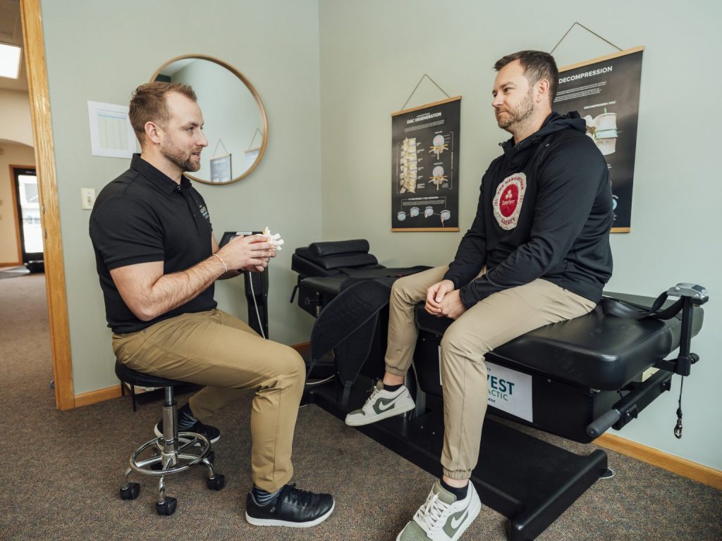 A doctor at Midwest Chiropractic & Wellness talking with a patient in an exam room